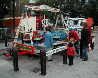 A small fairground ride on a street withpeople around it