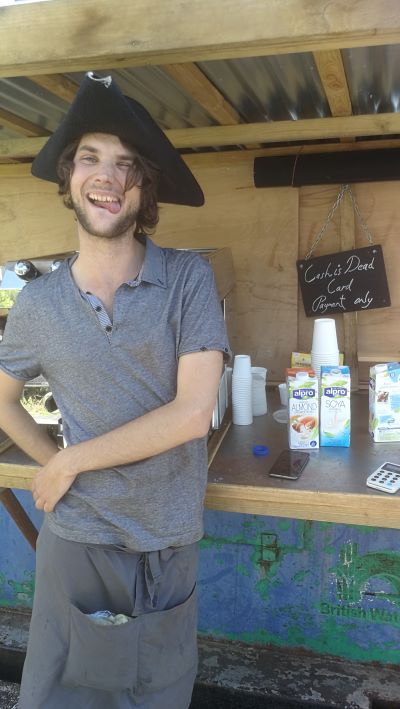 A young man laughs and pulls a face at his coffee stall on a boat