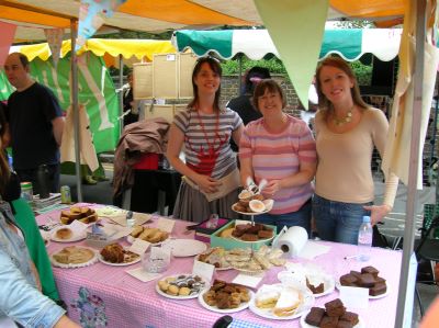 Cake stall close up - staff behind table laden with cake