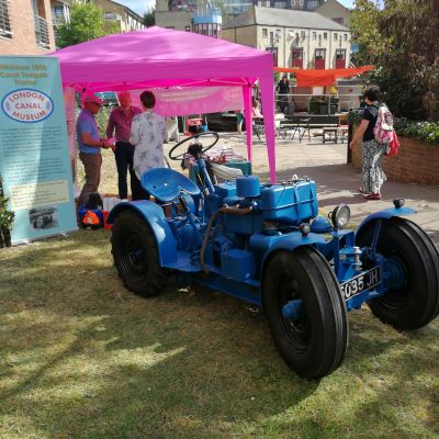 A blue small industrial tractor in front of a gazebo