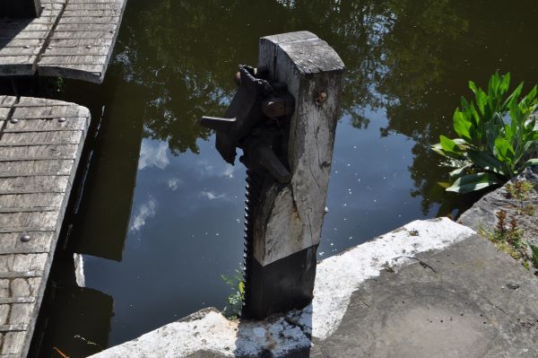 A wooden square post beside the canal and a lock gate